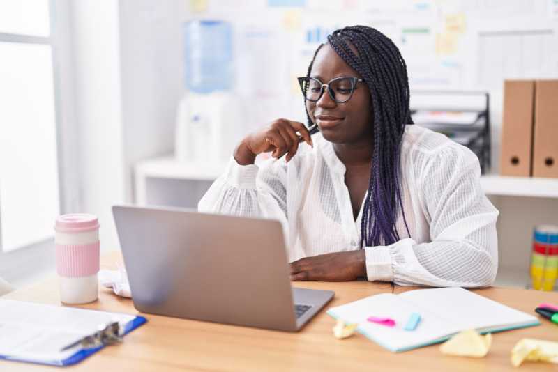 A woman is sitting at a desk working on her laptop.