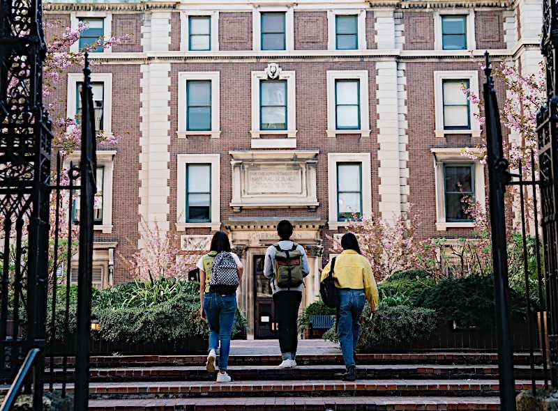 exterior of building with three students walking up the stairs