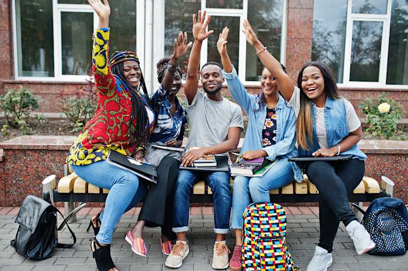 A group of college students waving at the camera. 